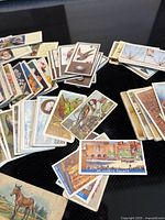 Spread of assorted cigarette cards showing varied themes and quantity