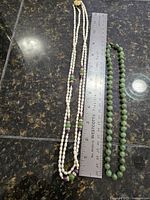 Both necklaces laid beside 12-in. ruler showing lengths and bead arrangement