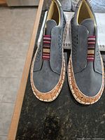 Top view of both shoes showing perforated grey uppers, elastic strap, cork trim, white outsole