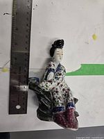 Porcelain figurine beside ruler measuring height