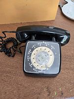 Front view of black rotary dial phone with handset resting on cradle