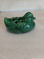 Right-side view of green ceramic duck flower frog showing perforations and molded feather detail