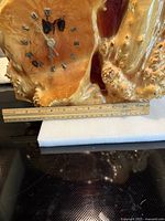 Front view showing clock face, burl wood texture, 12 in ruler for scale