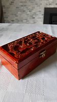 Carved Asian varnished wood cigarette box with brass clasp, showing entire closed box.
