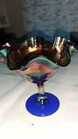 Full view of iridescent carnival glass candy dish with ruffled edge and blue stem