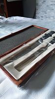 Meat carving set in fitted wooden box with foam padding, wrapped in protective plastic.