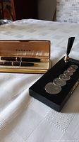 Parker fountain pen and propelling pencil in original case next to the pen holder with Canadian coins.