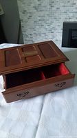 Front angle of vintage wooden jewellery box showing open top compartment and front drawer with metal handles.