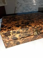 Closed view of vintage wooden jewellery box showing mottled brown and black exterior with metal clasp