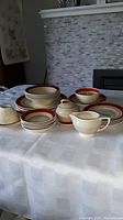 Full set displayed on a table showing various plates, bowls, cup, saucers, sugar bowl, and creamer.