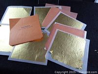 Stack of gold leaf sheets with peach backing and cover sheet marked Patent