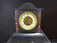 Front view of antique French slate mantel clock showing dial, case and stepped base