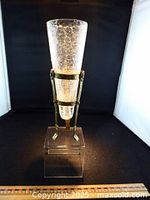 Front view of crackle glass vase seated in metal stand