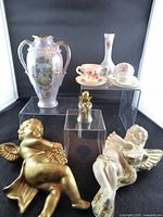 All items grouped: porcelain vase, bone china miniatures, Mikimoto figurine, two cherub plaques
