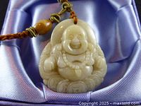 Close-up of jade Buddha pendant resting in satin-lined box