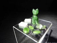 Front view showing all jade items: cat figurine, white bars, pendant, cabochons