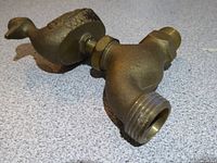 Side view of brass duck-handle faucet showing spout and threaded end