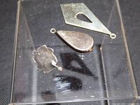 All three sterling silver pendants visible on clear stand