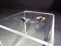Pair of sterling silver earrings showcasing blue topaz stones and clear accents on a display stand