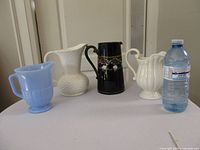 all four pitchers side by side with bottle for scale