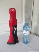 Front view showing red dress shape with black cat graphic beside water bottle for scale