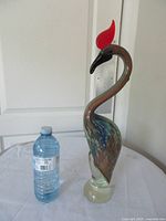 front view of glass bird next to bottle for scale