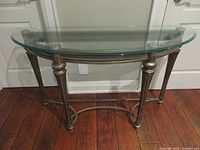 Front view of gold-tone metal console table with glass top