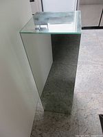 Angled view showing front and side mirrored panels and glass top