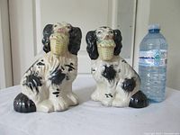 Front view of both ceramic spaniel figurines beside water bottle for scale