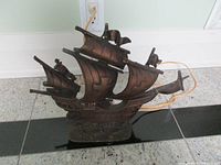Front view of metal ship lamp showing sail and hull detail