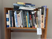 Books on a wooden shelf with titles including The High Sierra, Rock Dance, Mountaineering, Rock in the Road, Classic Treks, The Yosemite, and others related to climbing, hiking, and outdoor adventures.