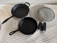 Photo of two cast iron pans and three splatter screens arranged on surface.
