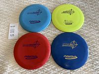 Four Innova Star plastic disc golf discs arranged flat on a textured surface showing top side with logos and weight stamps.