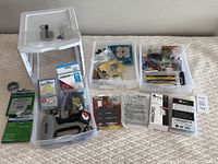 Wide shot of three plastic storage drawers containing assorted handyman supplies including tools, screws, nails, and repair kits.