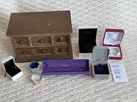 Wide photo showing the vintage wooden dresser jewelry box and various small jewelry boxes and pouches arranged in front.