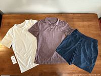 Top-down view of the white T-shirt, burgundy polo shirt, and navy shorts laid flat showing general condition and color.