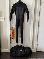 Full view of the wetsuit hanging on door with kayak rescue rope and black duffle bag on floor