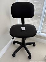Front view of black office chair showing squared cushioned seat and backrest, five-wheel base.