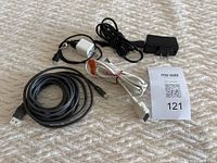 Various old cell phone cables and adapters including USB, mini-USB, micro-USB, 30-pin, and Thunderbolt to HDMI adapters laid out on a beige surface.