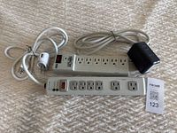 Photo showing two power bars placed side by side, one Belkin and one Tripp Lite, displaying multiple outlets and power switches.