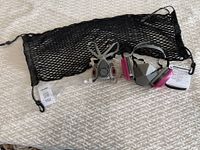 Photo showing both 3M 6000D half facepiece respirators, clear safety glasses, and black hanging net on white textured surface.