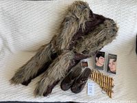 Costume vest, shoes, pan flute, and packaged prosthetic ears and horns laid out on a white surface