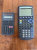 Casio fx-260 and Texas Instruments TI-83 calculators side by side on a wooden surface showing front view with buttons and screens.