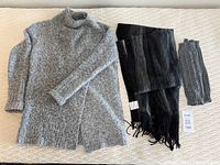 Full view of all three items: gray fuzzy cardigan, black wool shawl with fringe, and handknit gray leg warmers.