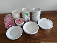 Photo showing white ramekins stacked, with lids and side plates in foreground