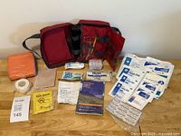 Photo of all contents laid out on wooden surface showing organized medical items and first aid manual.