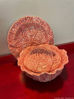 Front view of Bordallo Pinheiro pink cabbage leaf bowl with lid resting inside plate