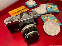 Full view of Nikon Nikomat FTn camera with lens, Kenko filter mounted, Nikon filter cases, lens cap, Kodak cleaning paper
