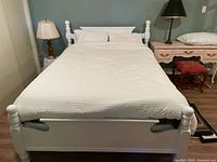 Bed assembled showing white wooden headboard, footboard, and side rails with mattress