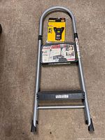 Ladder folded with DeWalt stud finder resting on top step